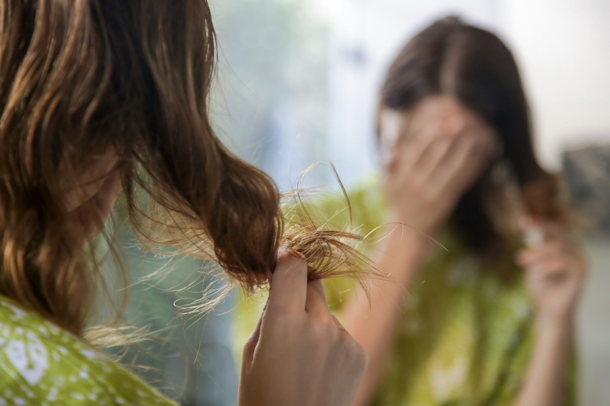 Hair ends. Девочка заканчивает волосы. В волосах запутанные листики. Девушка смотрит на свои кончики.