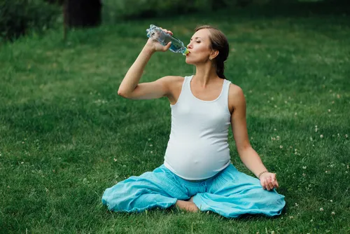 embarazada bebe agua en botella de plástico